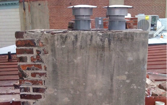 Historic masonry and tuckpointing work on a brick chimney with modern vents.