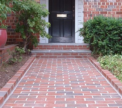 Beautiful brick pathway leading to a historic home door with detailed masonry work.