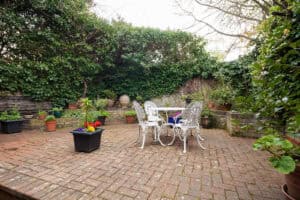 Outdoor brick patio with garden furniture and potted plants, showcasing masonry work.