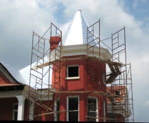 Historic brick building under renovation with scaffolding and a pointed roof.
