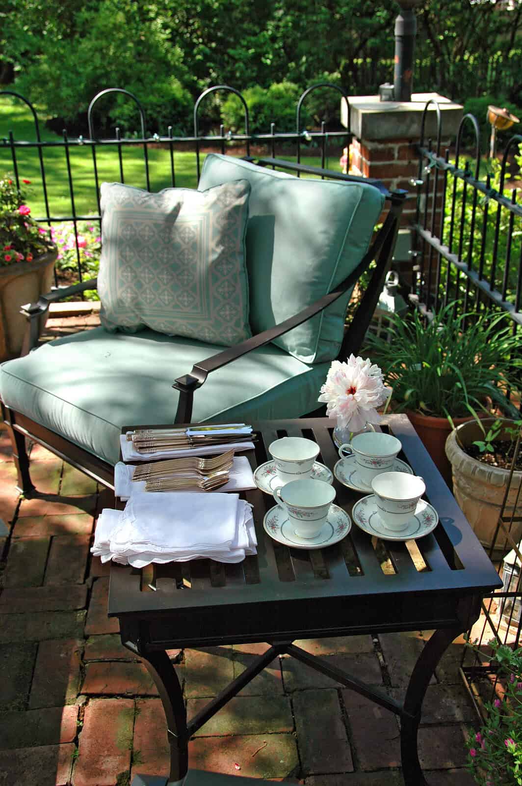 Elegant outdoor patio with vintage-style cushions and tea set.