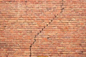 Cracked historic brick masonry wall showing signs of deterioration.