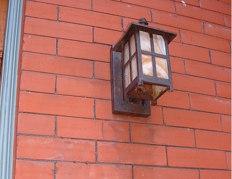 Exterior wall lantern mounted on red brick wall, vintage style lighting fixture.