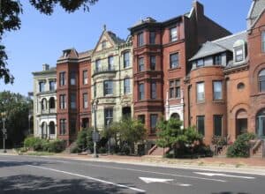 Row of historic brick buildings with detailed masonry and tuckpointing in a city neighborhood.