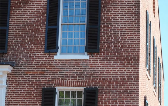 Close-up of historic brick masonry with black shutters on a Renaissance building.