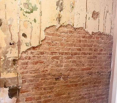Close-up of historic brick wall with damaged plaster and mortar repair.