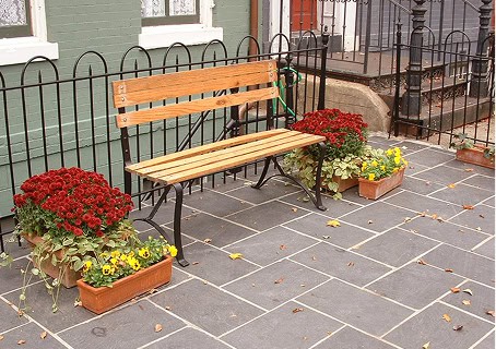 Bench with flower pots on a paved sidewalk in front of a historic building.