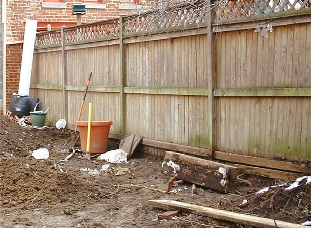 Masonry repair and tuckpointing work on a wooden fence and foundation.
