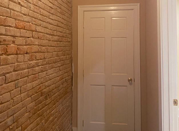 Interior door with brick wall and white trim, showcasing masonry craftsmanship.