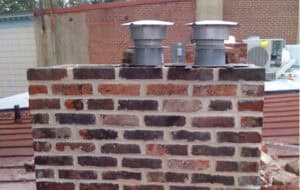 Historic brick chimney with modern vent caps and tuckpointing work.